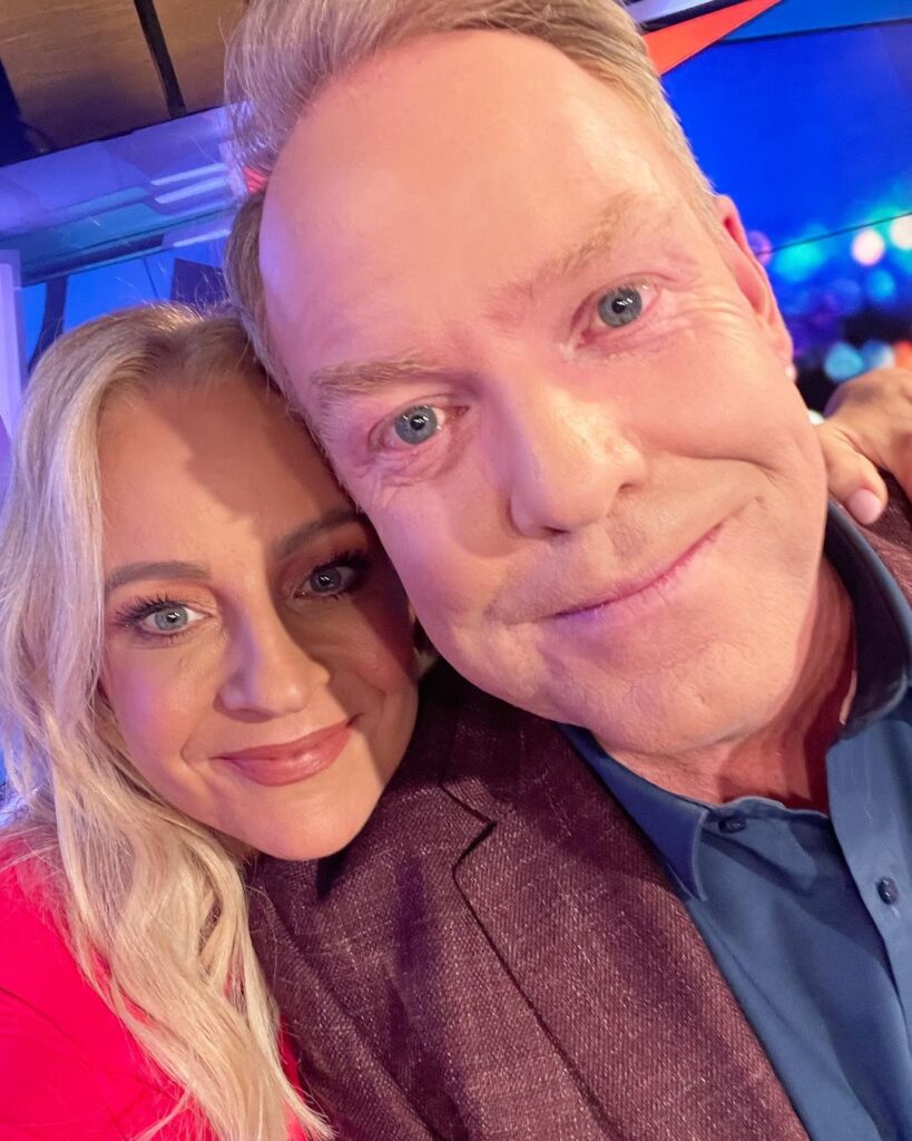 Carrie Bickmore in the red sexy outfit while taking picture with her husband while looking towards camera