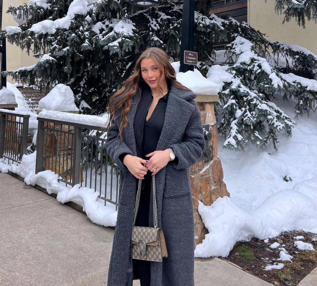 Marissa Layne Lawrence in the full black outfit pair with grey over coat and matching bag while poses for a photograph