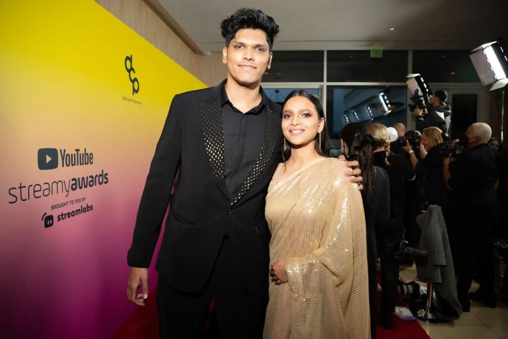 Mithilesh Patankar in the full black 3 piece outfit while taking a photo with his wife