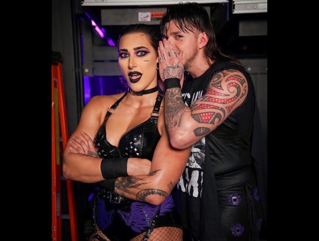 Rhea Ripley in the wrestling costume while looking toward camera and taking picture with his collegue