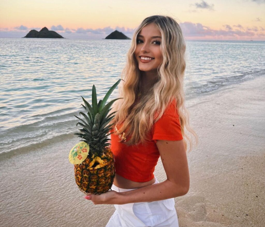 Emily Dobson in the orange crop t-shirt pair with white pant while looking towrads camera