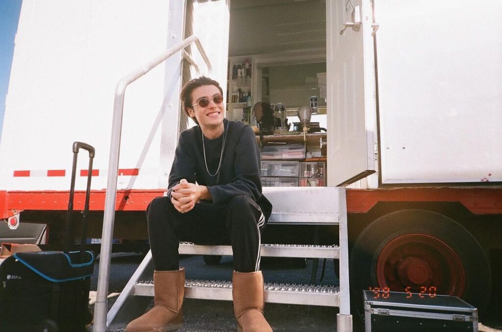 Felix Mallard in the black sweatshirt pair with matching trouser and brown shoes while smiling towards camera