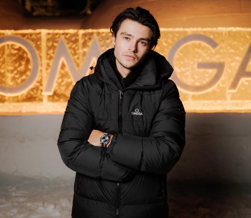 Felix Mallard in the black waterproof jacket pair with watch while looking towards camera