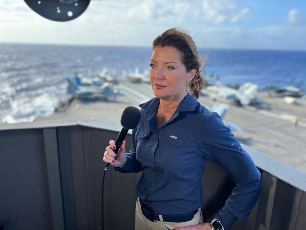 Norah O'Donnell in the blue dress shirt pair with matching pant while taking a photograph