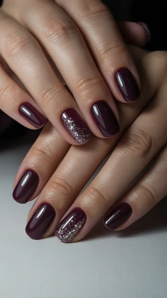 Deep plum winter sparkly nails with a glossy finish and subtle silver glitter accent nail, elegant winter nail design for 2026