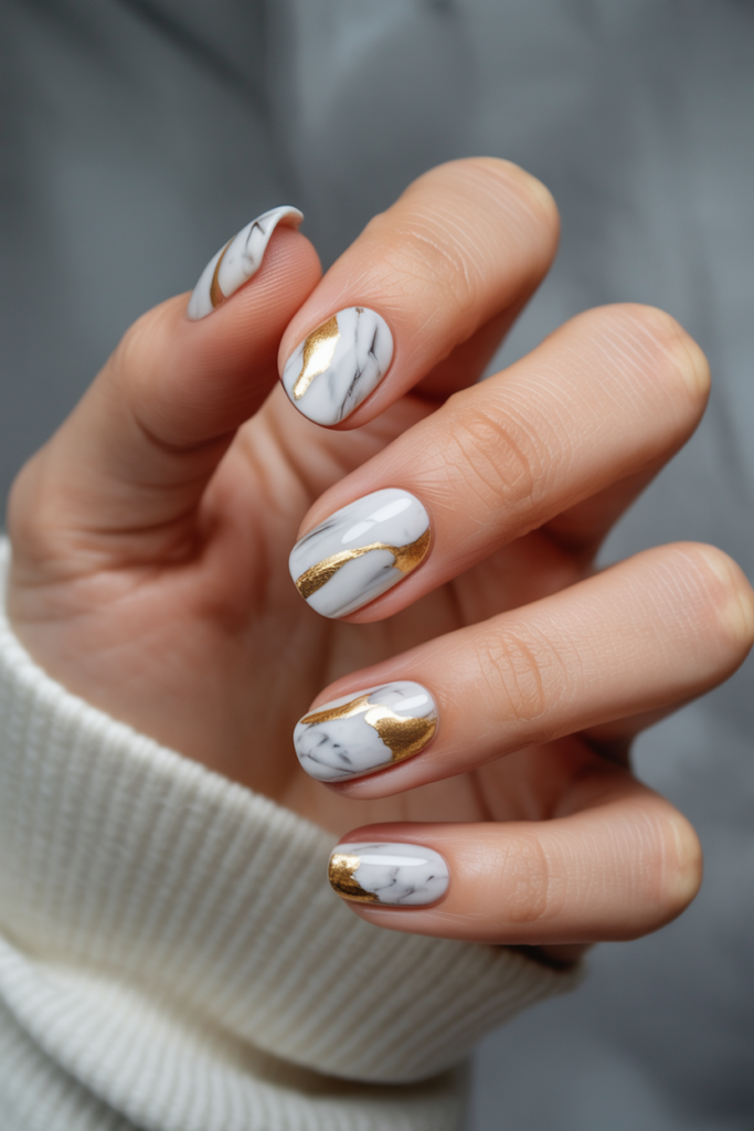 White marble nails with gold foil accents for luxurious New Year’s Eve nail design