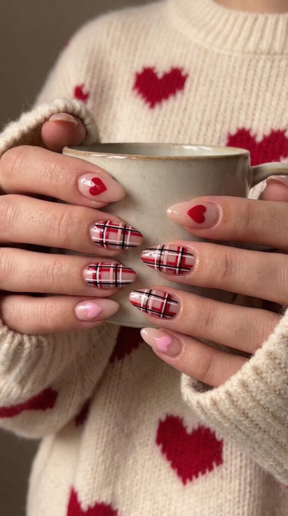 Red and black plaid nail art with heart accents on short round nails