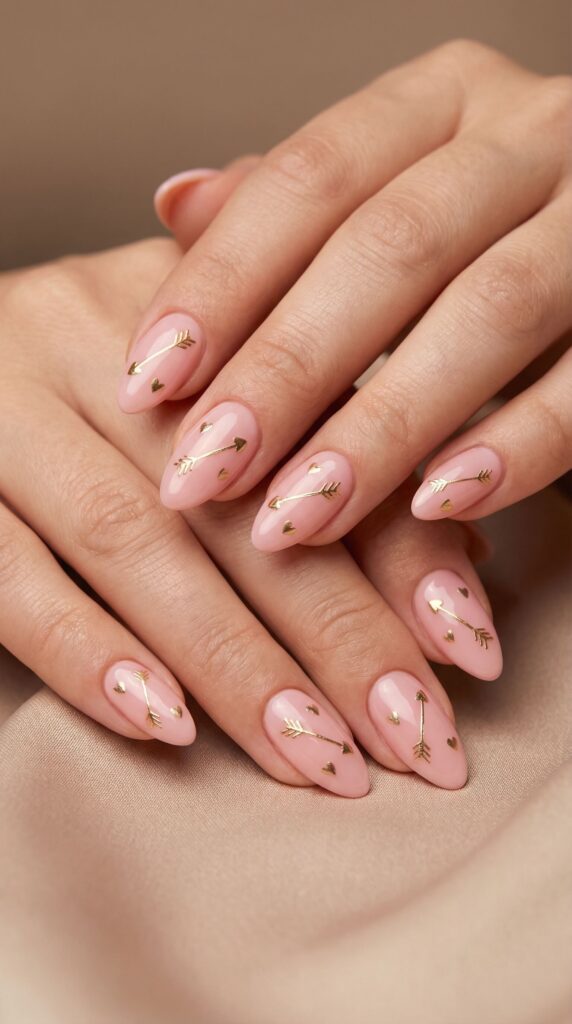 Soft pink nails with gold Cupid's arrow and heart designs