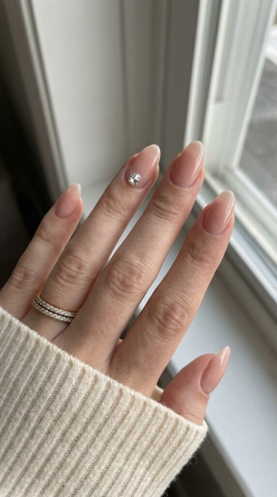 Minimalist nude nails with single crystal rhinestone accent