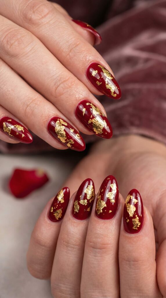 Deep red glossy nails with gold leaf foil accents