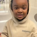 Baby Woo Wop in the off white hoodie pair with black pants while smiling towards camera