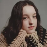 Bella Ramsey in the brown and black wool shirt while looking towards camera for taking a picture