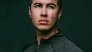 Damian Romeo in the black front zip shirt while looking towards camera for taking a picture