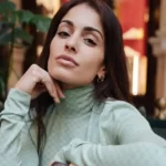 Hiba Abouk in the green high neck shirt pair with small earrings while looking towards camera