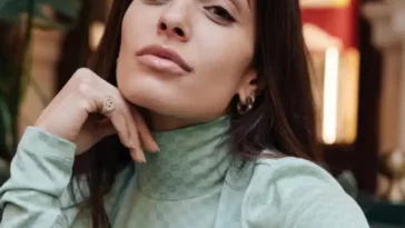 Hiba Abouk in the green high neck shirt pair with small earrings while looking towards camera