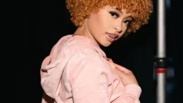 Ice Spice in the crop pink hoodie pair with purple shorts while looking towards camera