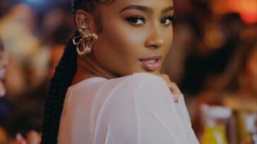 Kayla Nicole in the white crop top pair with elegant earnings while looking towards camera