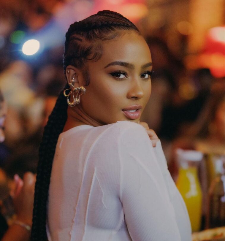 Kayla Nicole in the white crop top pair with elegant earnings while looking towards camera