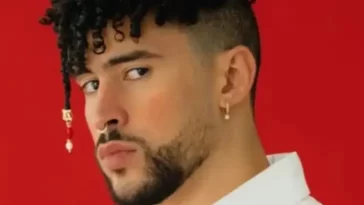 Bad bunny in the white shirt pair with elegant jewellery while looking towards camera