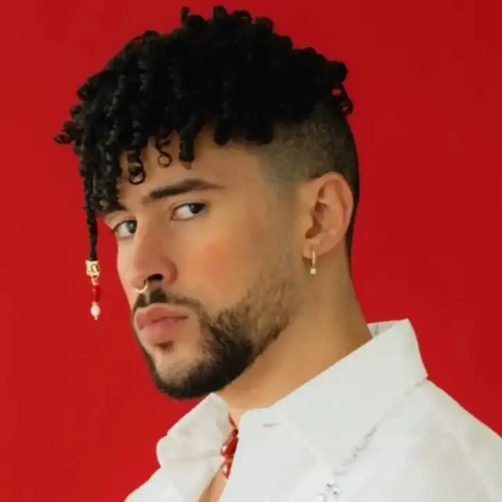 Bad bunny in the white shirt pair with elegant jewellery while looking towards camera