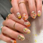 Short nails with fruit nail art using orange, yellow, and pink nail paint