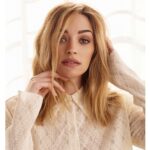 Brianne Howey in the peach front button top paired with blue jeans while looking camera