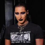 Rhea Ripley in the black crop t-shirt pair with matching pant while smiling towards camera