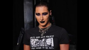 Rhea Ripley in the black crop t-shirt pair with matching pant while smiling towards camera