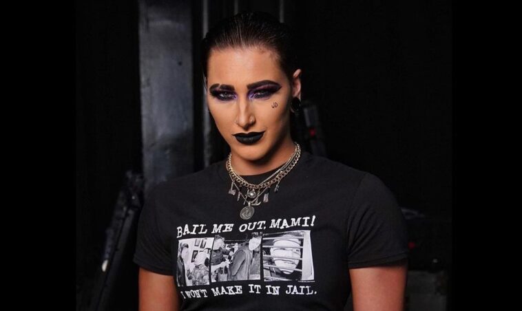 Rhea Ripley in the black crop t-shirt pair with matching pant while smiling towards camera