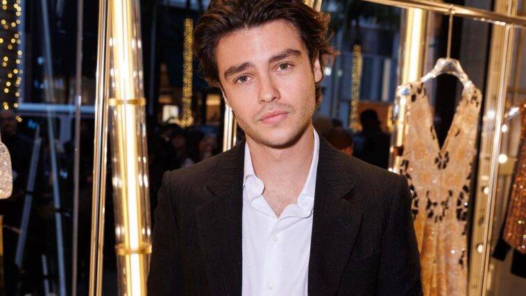 Felix Mallard in the white dress shirt pair with white coat and dress pant while poses for a photo