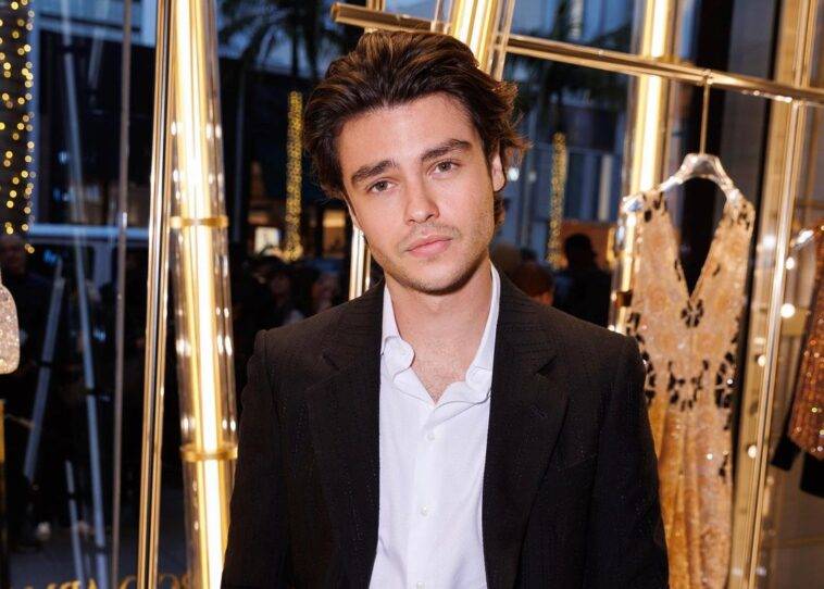 Felix Mallard in the white dress shirt pair with white coat and dress pant while poses for a photo