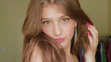 Jenny Roselie in the grey sexy top pair with drop earrings while looking towards camera