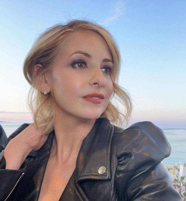 Sarah Michelle Gellar in the black jacket and diamond studs while poses for a photo