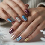 Hands showcasing winter sparkly nails with blue chrome, champagne shimmer, burgundy metallic polish, gold glitter accents, and snowflake nail art, elegant winter nail designs for 2026