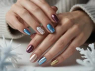Hands showcasing winter sparkly nails with blue chrome, champagne shimmer, burgundy metallic polish, gold glitter accents, and snowflake nail art, elegant winter nail designs for 2026